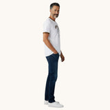 Capitandenim white unisex t-shirt with ocre trim and a graphic print. Model wears dark wash jeans and white sneakers.
